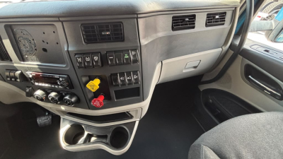 Peterbilt 579 cabin dashboard area showing control switches, knobs, and cup holders.