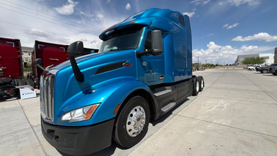 Peterbilt 579 conventional sleeper truck in blue, front-left view showing cab, hood, and front wheel.