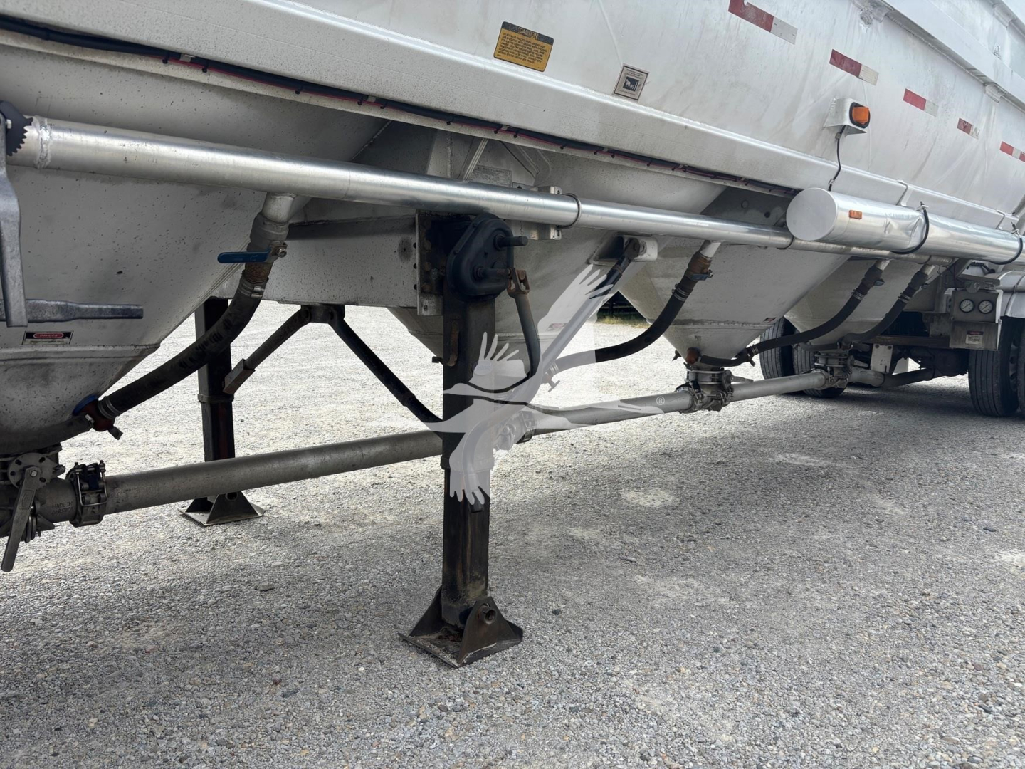 Trailer undercarriage showing support legs and underside of Heil 1625 Super Flo pneumatic trailer with hoses and brackets visible.