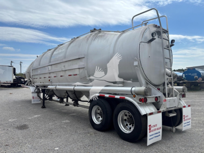 Twin-axle Heil 1625 Super Flo pneumatic dry bulk trailer with rounded cylindrical tank, silver metal finish, rear ladder, and dual rear lights.