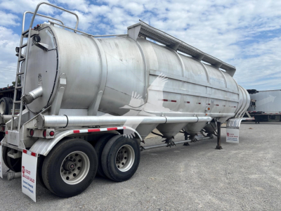 Trailer rear-left side showing a cylindrical Heil 1625 Super Flo pneumatic dry bulk trailer with dual rear axles, ladder, and top manway; VIN sticker not visible.