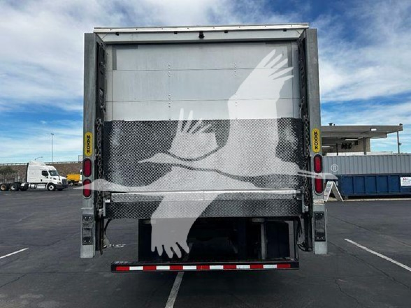 Rear view of a 2020 Hino 268a box truck showing cargo bed and taillights, with partial view of truck yard.