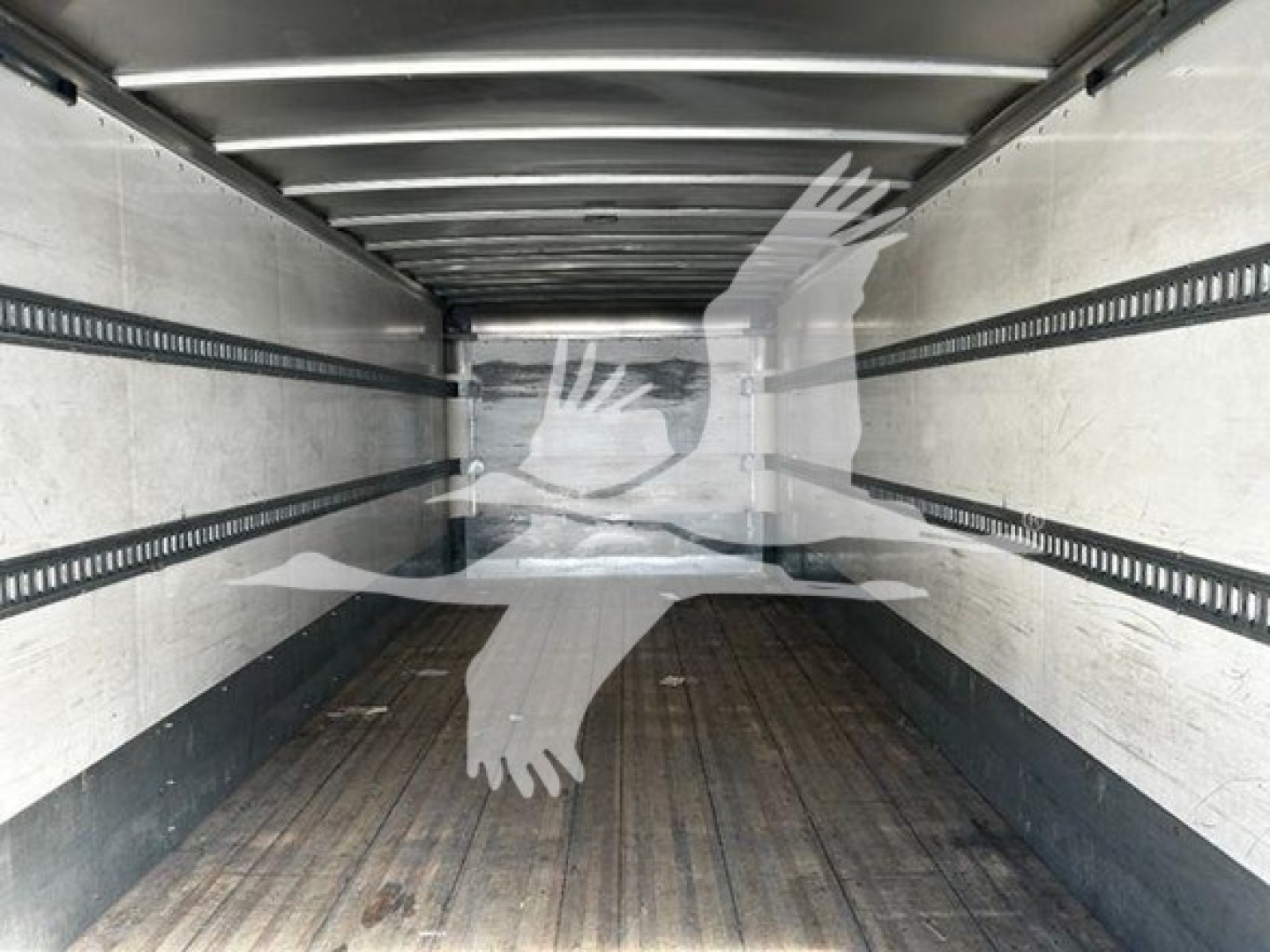 Truck trailer interior cargo area view with metal side rails and wooden floor, empty space.