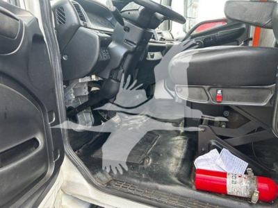 Interior of a 2020 Hino 268A cab showing driver's seat, steering wheel, pedals, and floor with a fire extinguisher and paperwork on the floor.