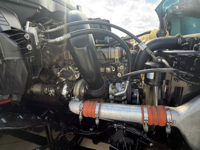 Truck engine bay showing various hoses, pipes, and components in a Freightliner Cascadia 126 engine bay.
