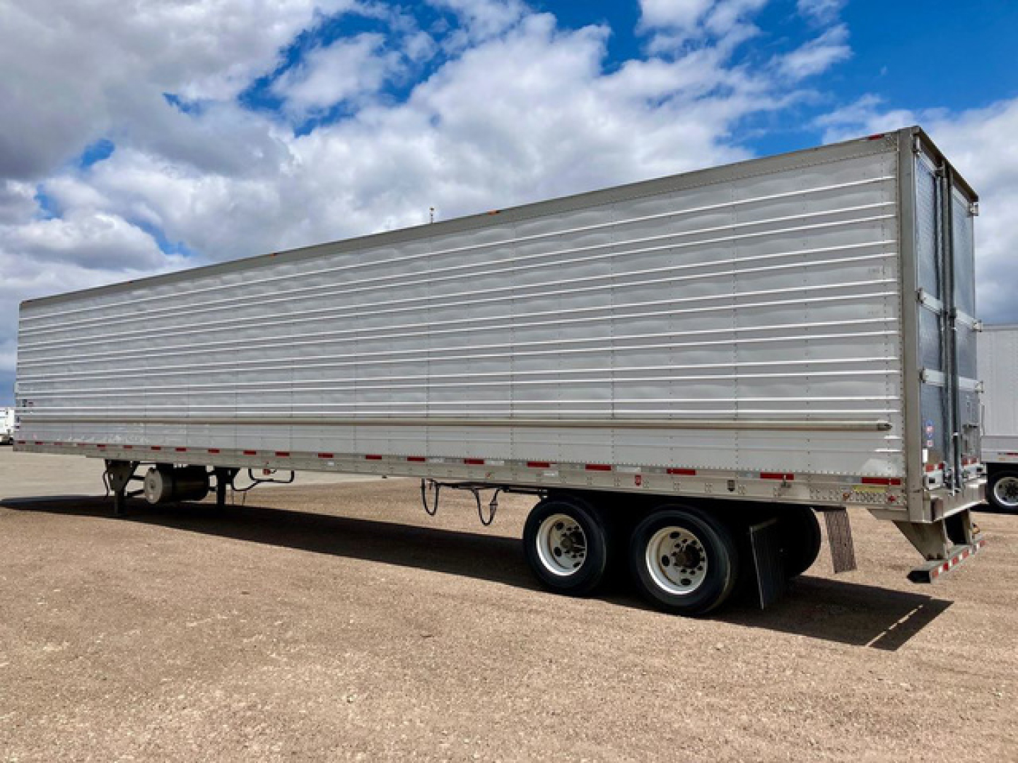 Trailer side view showing a 2022 Utility reefer trailer with aluminum corrugated side, dual rear axles, and rear doors closed.