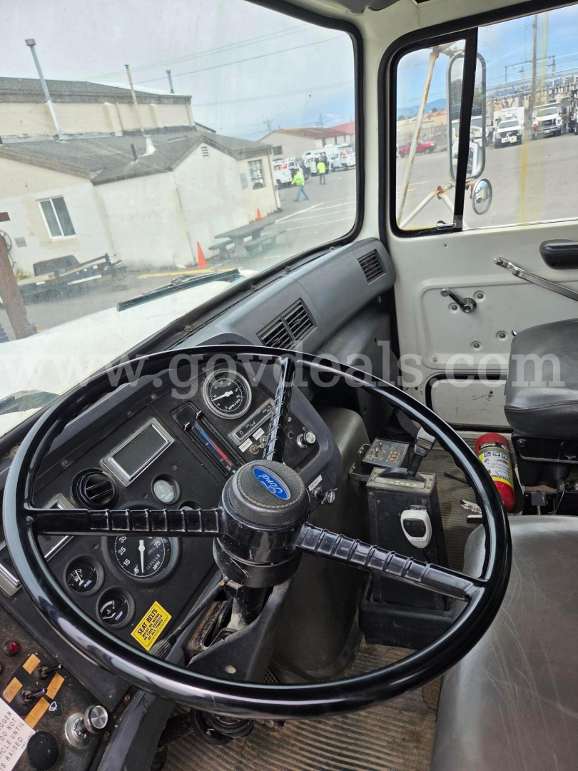Truck cab interior showing steering wheel and dashboard of a 1992 Ford LN8000F with gauges, switches, and a center console.