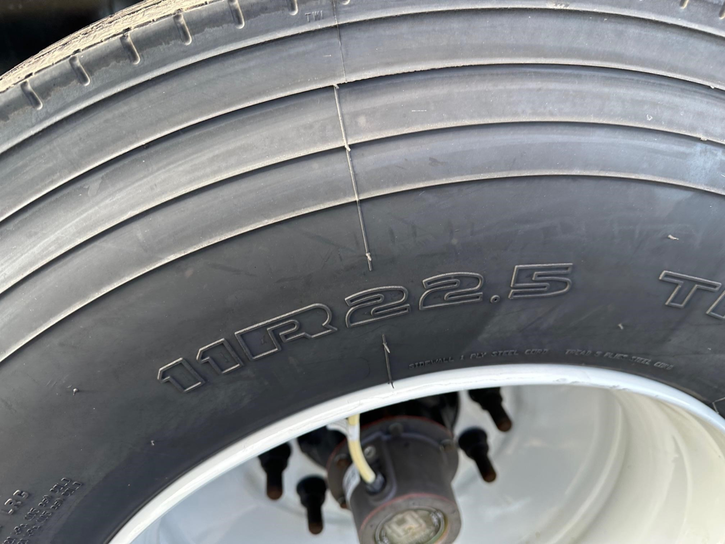 Tire close-up on a Manac 53' combo flatbed trailer showing tire size 11R22.5 and wheel hub area.