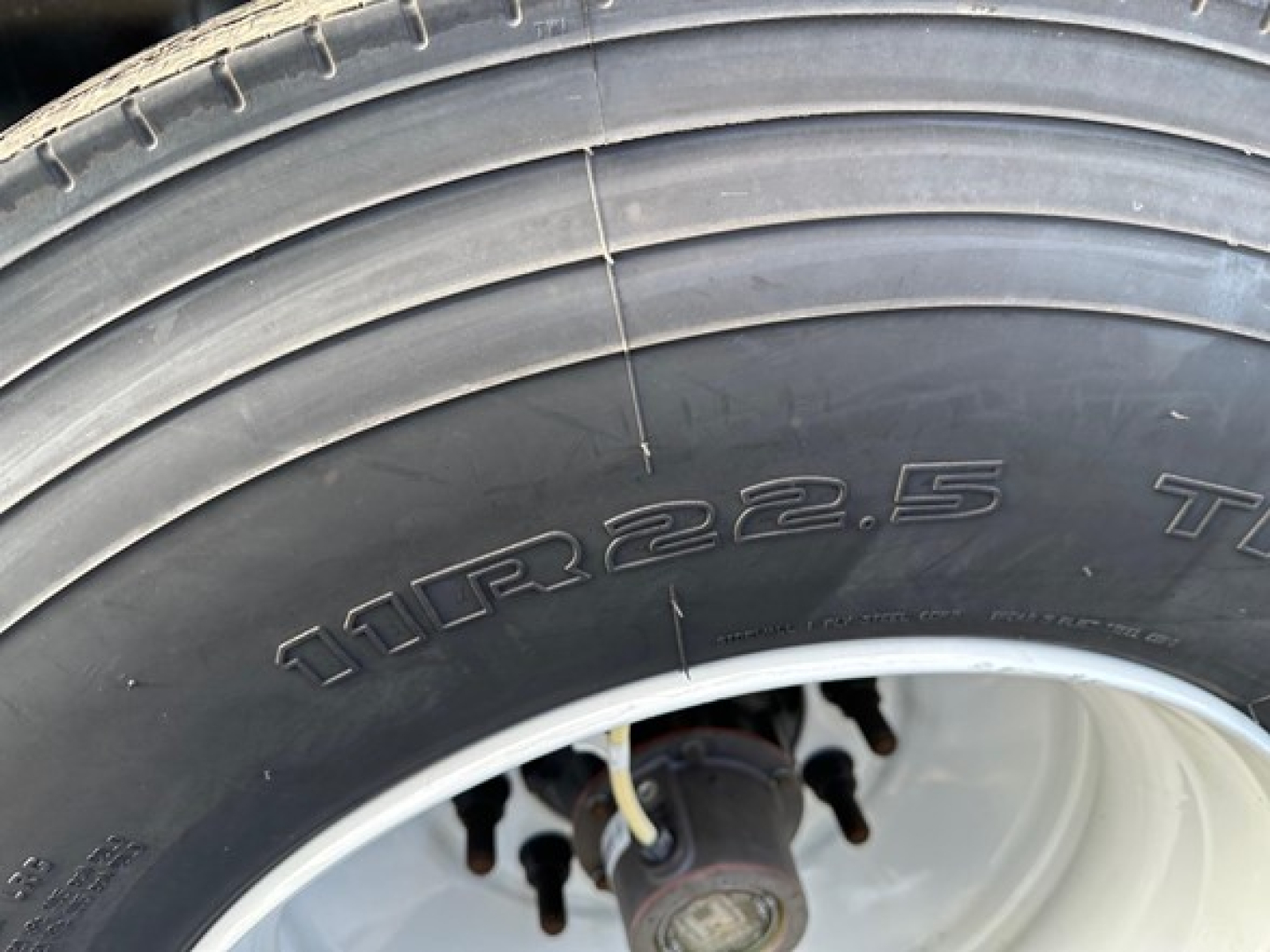 Front tire showing tread and sidewall with embossed tire size 11R22.5 and wheel hub area.