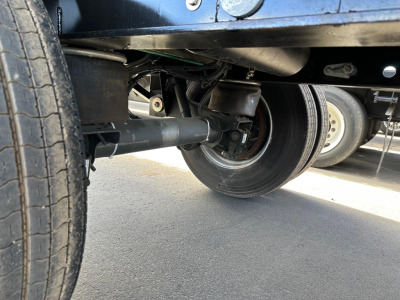 Manac 53' combo flatbed trailer undercarriage showing axle, suspension, and wheel assembly.