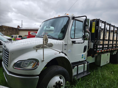 Freightliner M2 106 flatbed truck side view showing cab and cargo bed with reflective marker lights