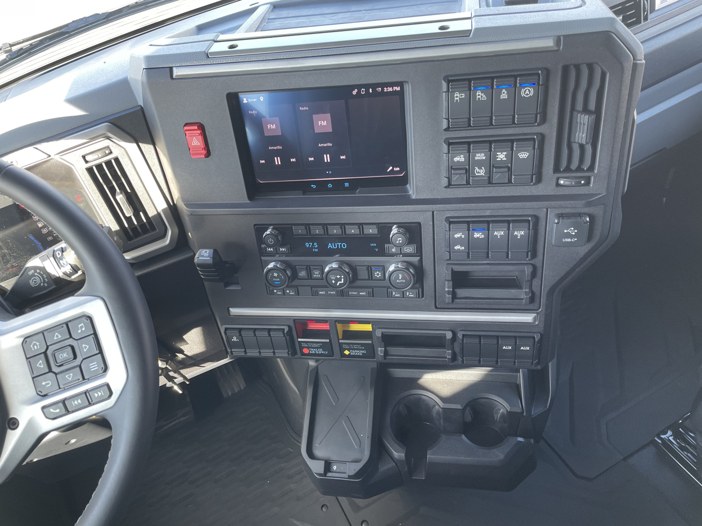 Dashboard of a 2026 Mack PR64T64 truck showing touchscreen display, climate controls, switches, and cup holders.