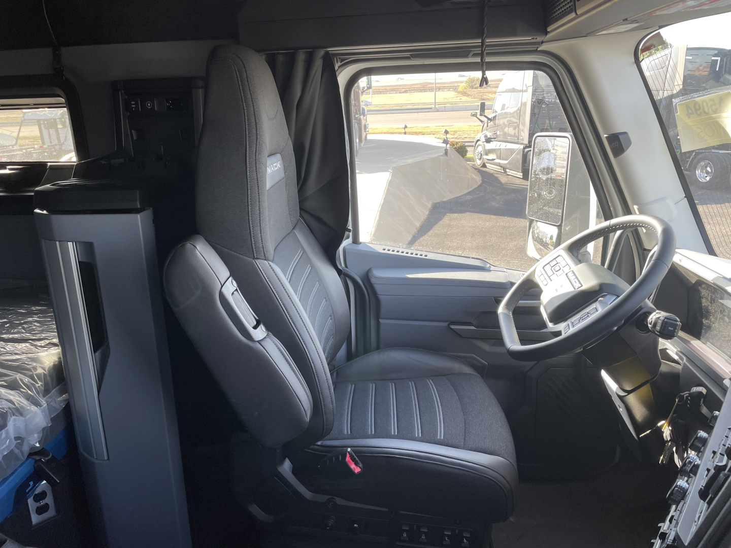 Cab interior of a 2026 Mack PR64T64 truck showing driver seat steering wheel and dashboard with front passenger seat