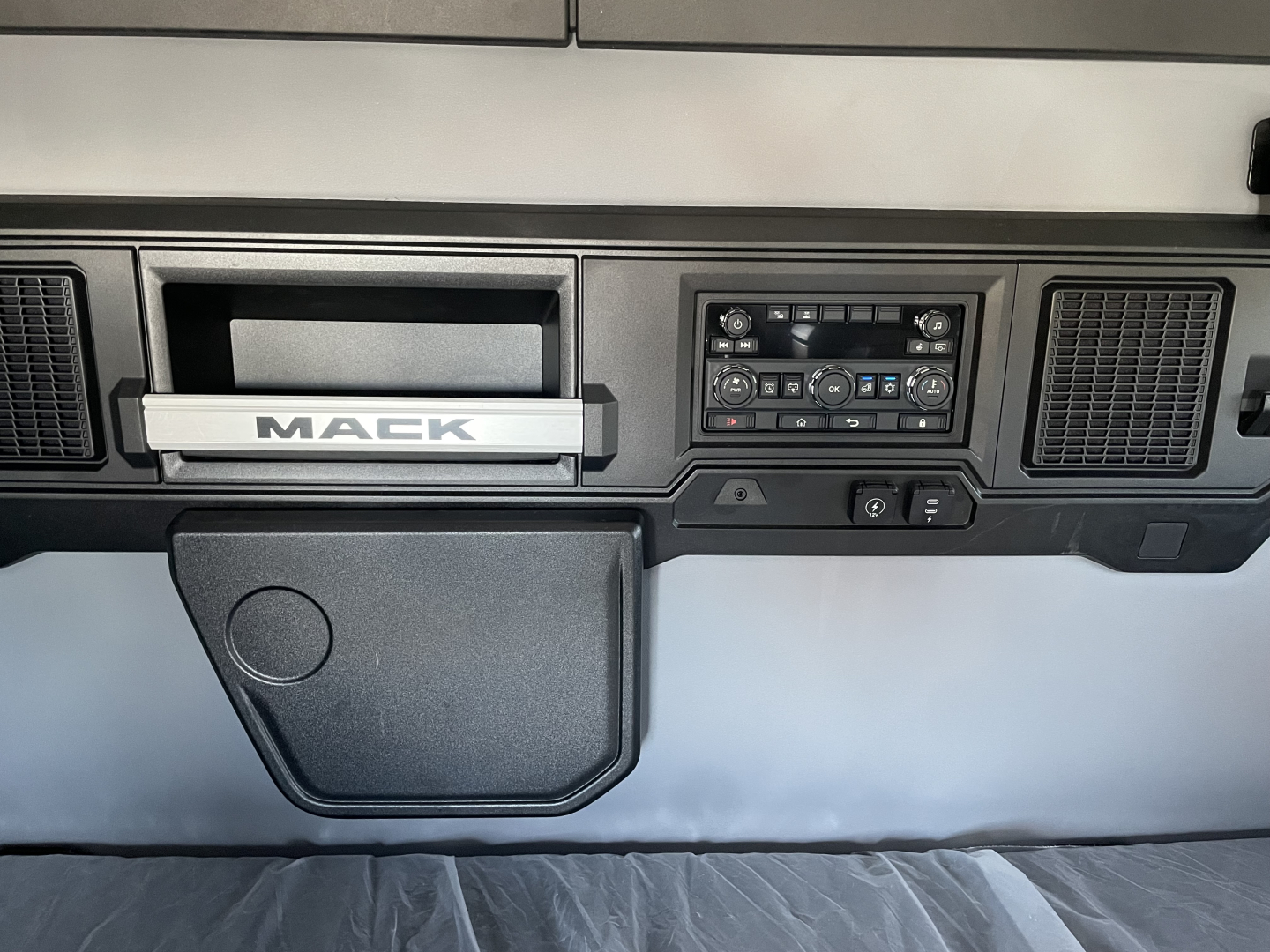 Mack PR64T64 dash area showing infotainment controls and storage compartment.