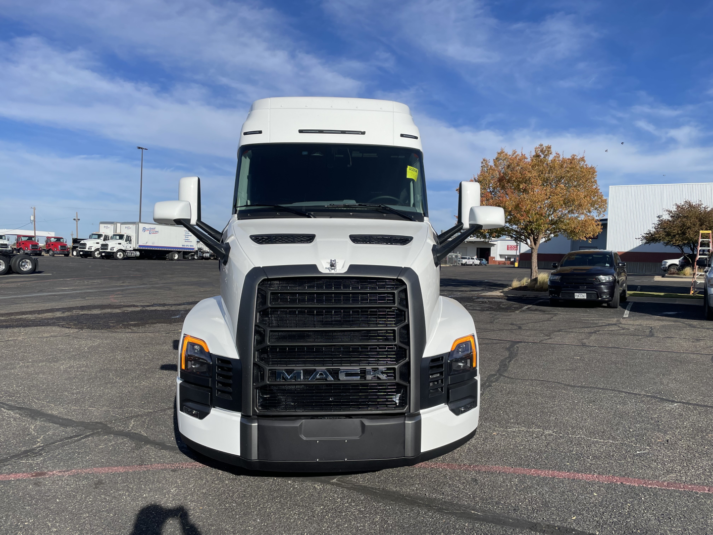 Front view of a white 2026 Mack PR64T64 conventional sleeper truck in a dealership lot, with large grille and headlights visible