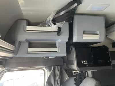 Cab interior of a 2026 Mack PR64T64 showing storage compartments with latches and a black dashboard area.