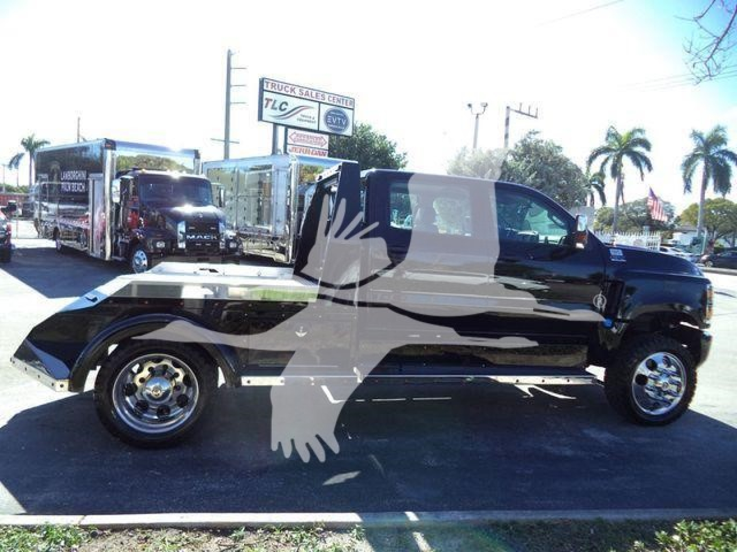 Truck side view showing a black pickup with extended cab and chrome wheels in a dealership lot