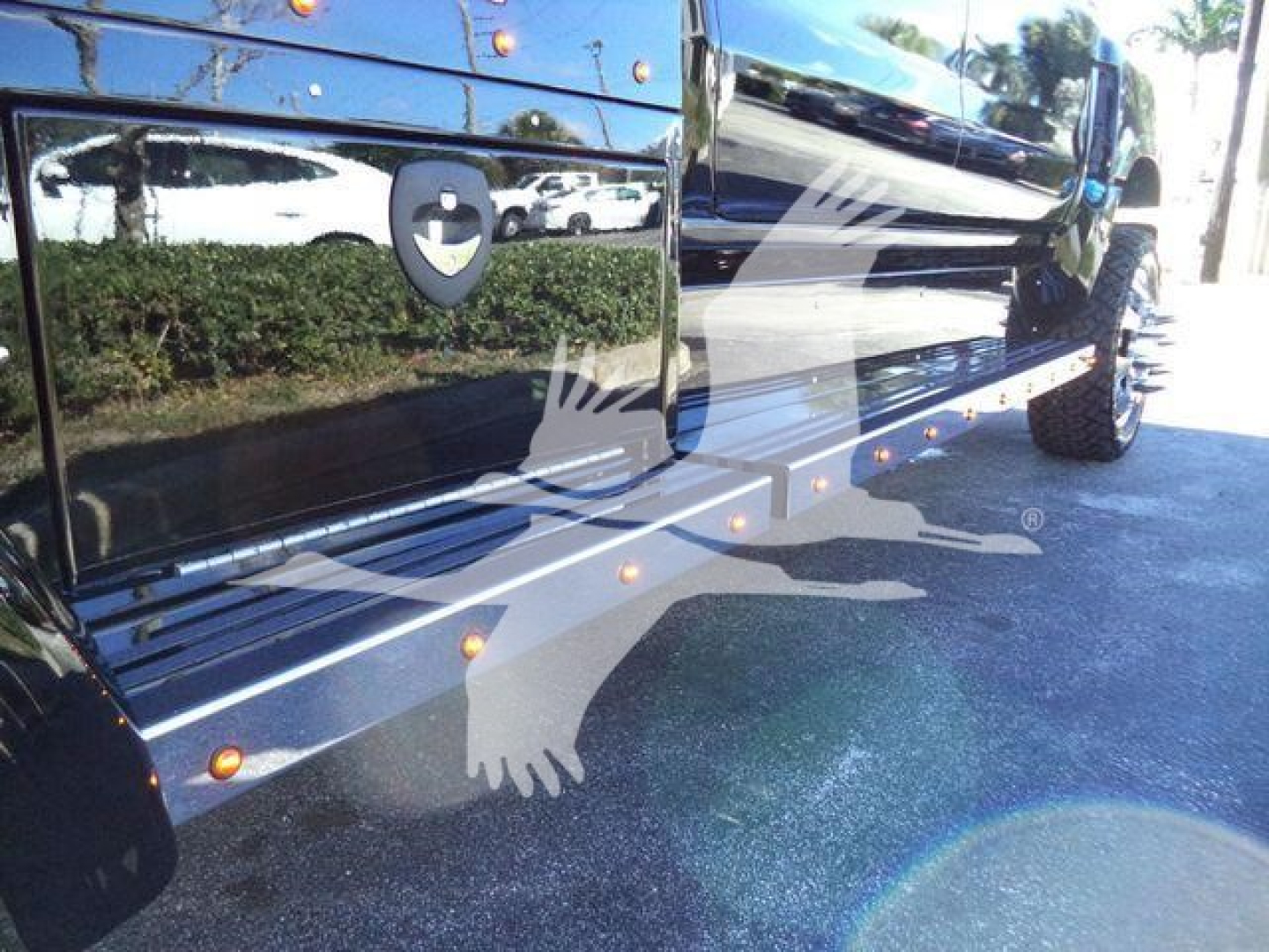 Side view of a new 2023 International CV truck with chrome running boards, steps, and reflected surroundings in black paint.