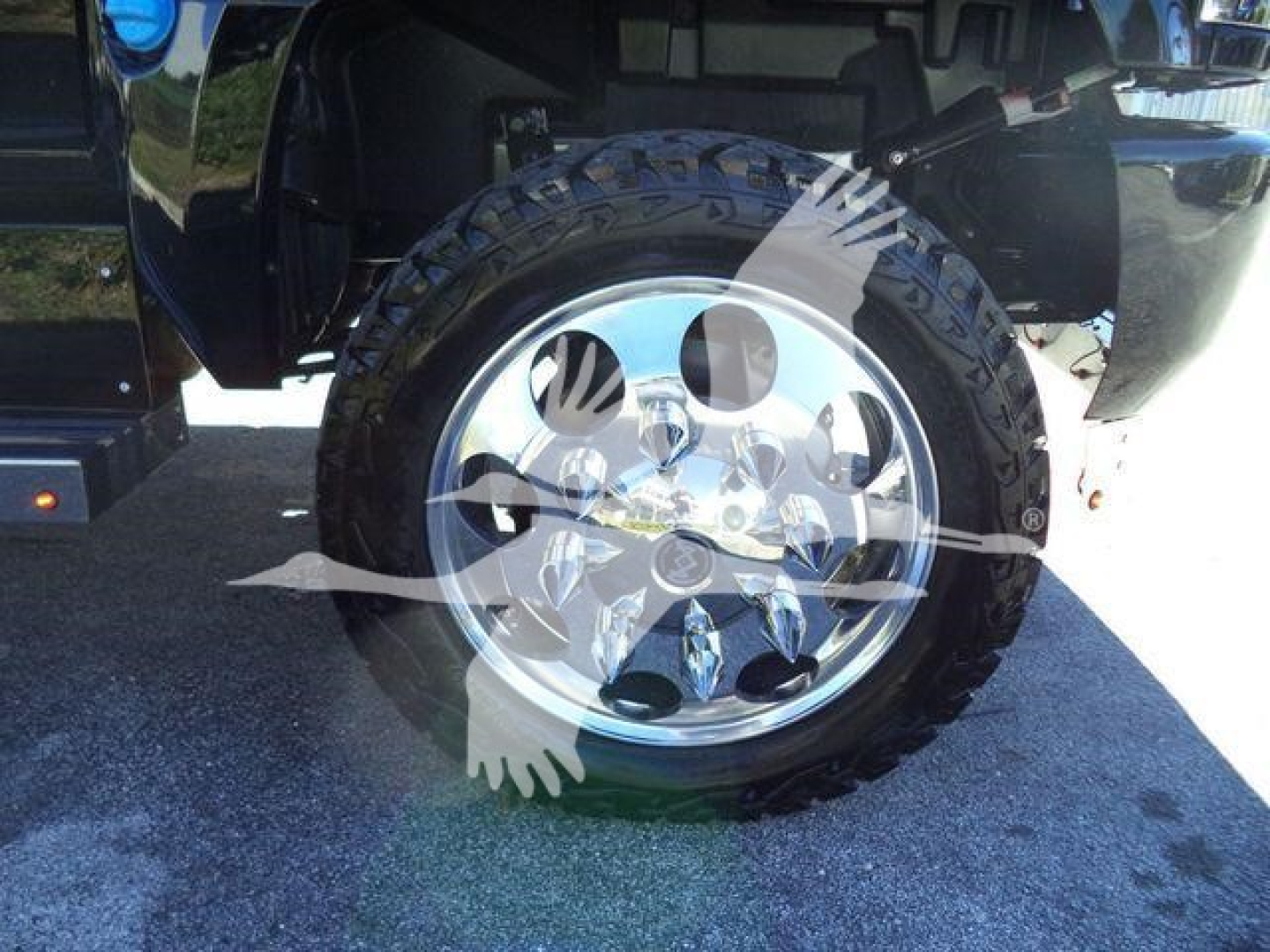 Wheel and tire on a pickup truck with shiny chrome rim and rugged tire. Partial truck bed and fender visible.