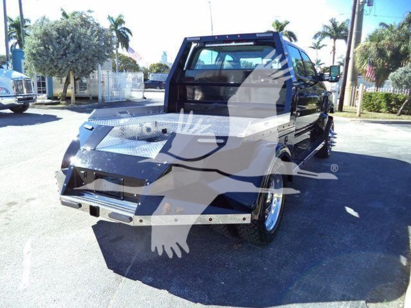 Flatbed tow truck showing rear and cab with watermark overlay