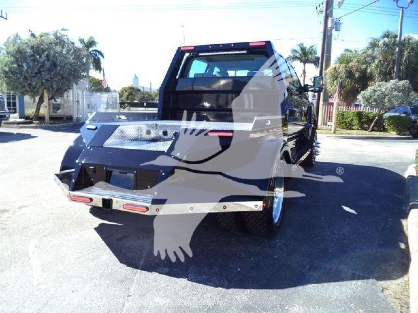 Back of a black 2023 International CV truck with a flatbed/dump bed and extended rear hitch assembly.