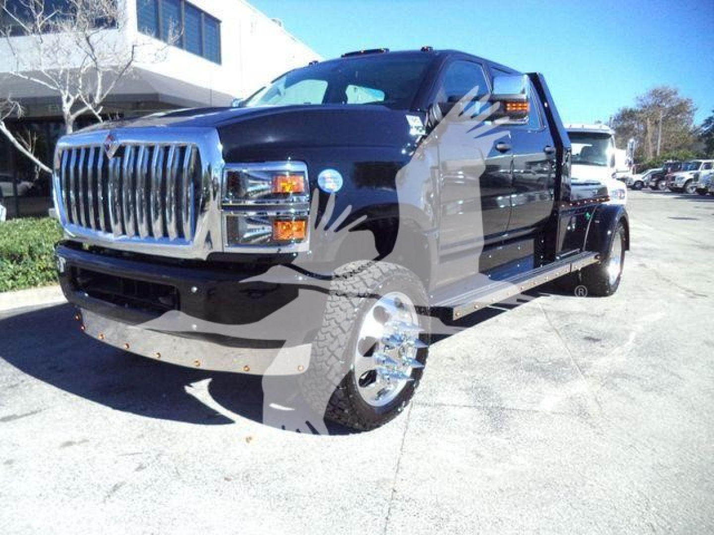 2013 International CV or similar heavy-duty tow truck/hauler with black cab and chrome grille, large front bumper, dual rear wheels visible.