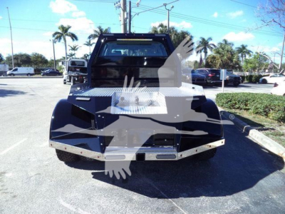 Front view of a 2023 International CV truck in a dealership lot, showing a black tow hitch bed with diamond plate and chrome trim.