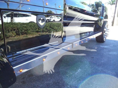 Side view of a new 2023 International CV truck with chrome running boards, steps, and reflected surroundings in black paint.