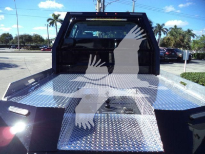 Pickup truck flatbed with diamond tread metal deck and wheel-lift bed in a yard.