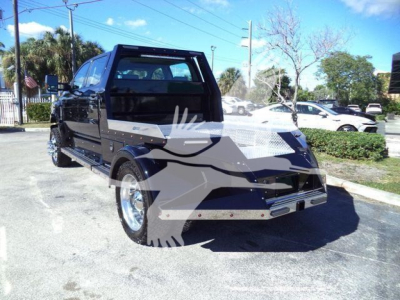 Black customized pickup truck with flatbed and lifted cabin, front grille with diamond plate, dual exhaust, alloy wheels, in a parking lot.
