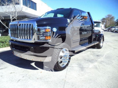 2013 International CV or similar heavy-duty tow truck/hauler with black cab and chrome grille, large front bumper, dual rear wheels visible.