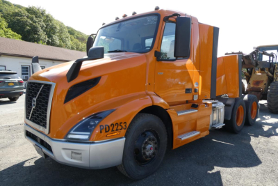 Volvo VNR64T300 truck in orange cab with PD2253 markings, side exhaust, conventional daycab, 6x4 axle configuration visible.