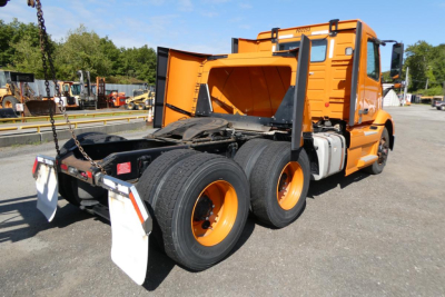 Orange Volvo VNR64T300 conventional daycab tractor rear view showing fifth wheel area and dual rear axles.