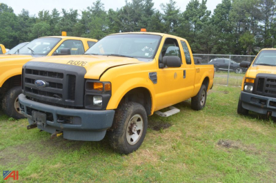 2008 Ford F-250 Super Duty extended cab pickup truck in yellow with black bumper, parked on grass among other yellow trucks.