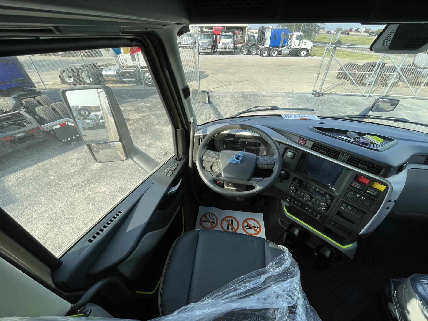 Interior of a Volvo VNL64T860 truck cab with steering wheel, dashboard, and driver seat visible. Displays control panel, center console, and large side window.