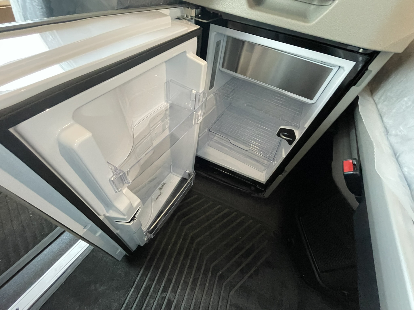 Volvo VNL64T860 cab interior showing open refrigerator and small freezer compartment in a front kitchenette area.