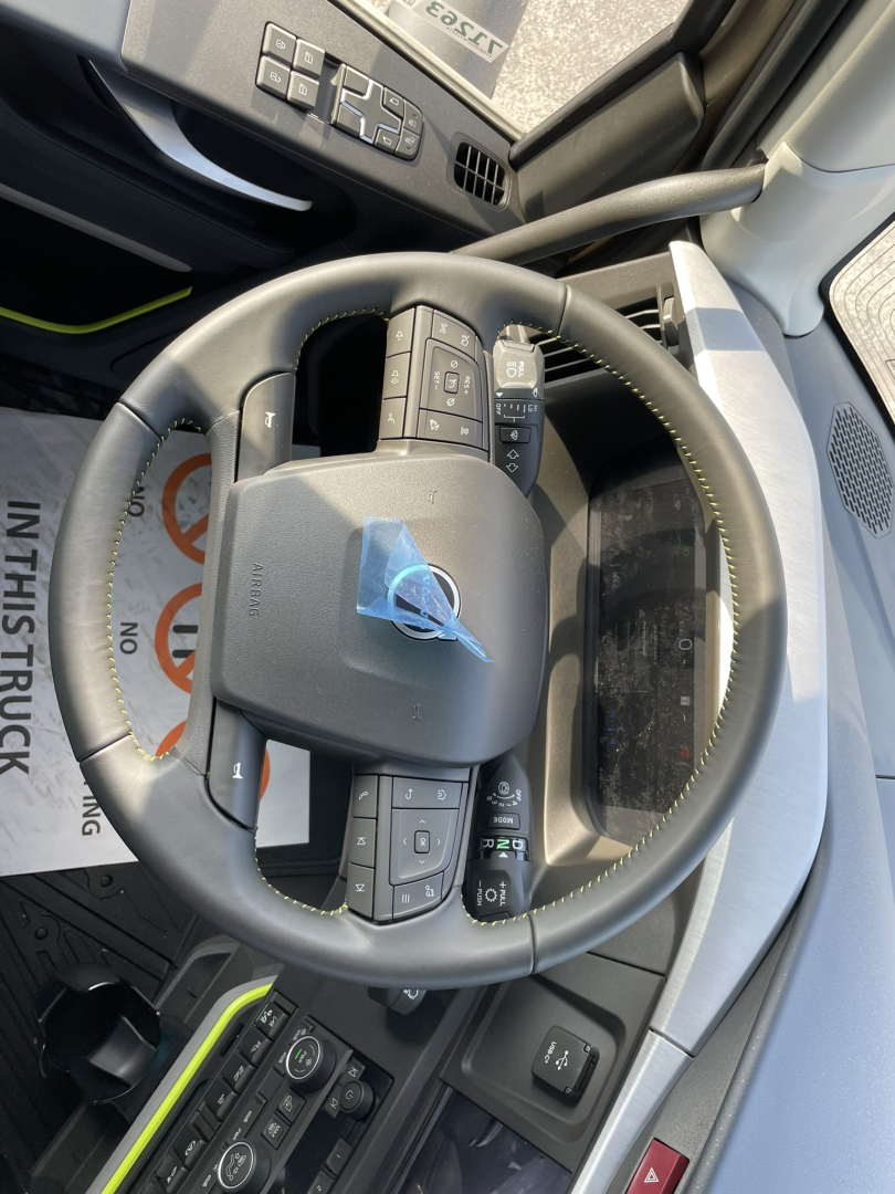 Volvo truck steering wheel with controls in cabin view showing dashboard and keys in ignition area.