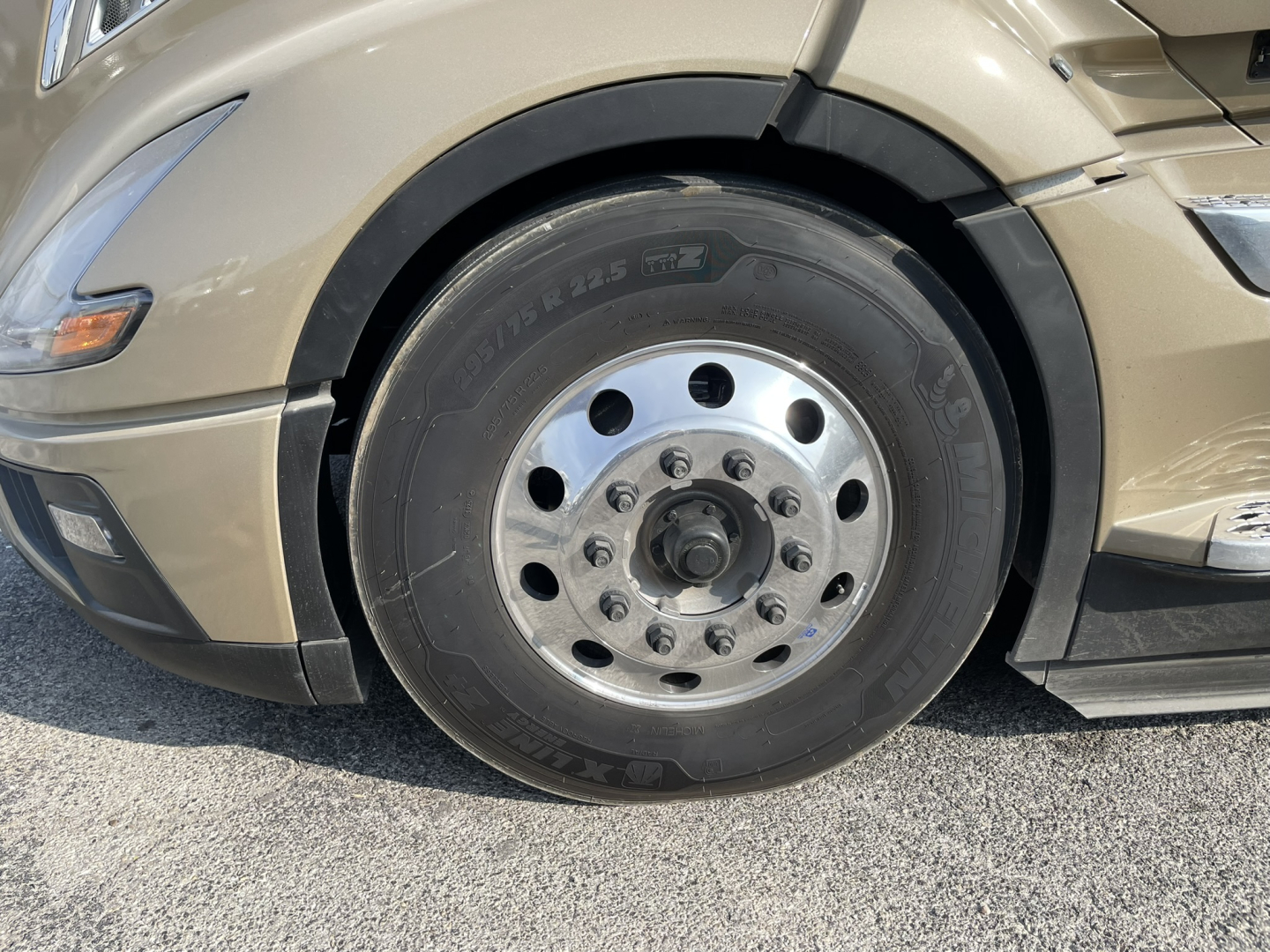 Truck wheel close-up showing steel hub and tire on Volvo VNL64T860 sleeper cab front wheel area.