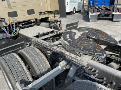 Volvo VNL64T860 chassis with dual fuel tanks and fifth wheel area visible, view of rear cab area and driveshafts, no text legible