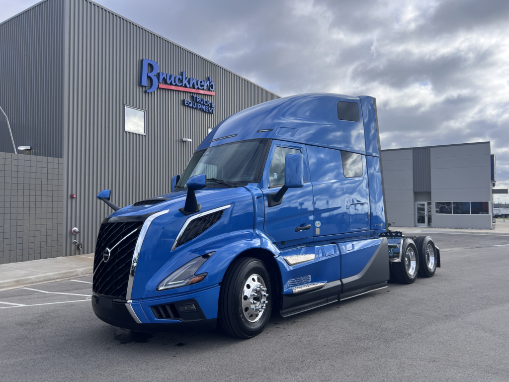 Volvo VNL64T860 truck in blue parked outside dealership.