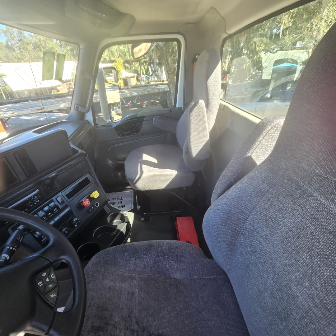 Cab interior of a 2018 International LT625 conventional truck showing driver's seat, passenger seat, steering wheel, dashboard with controls and vents.
