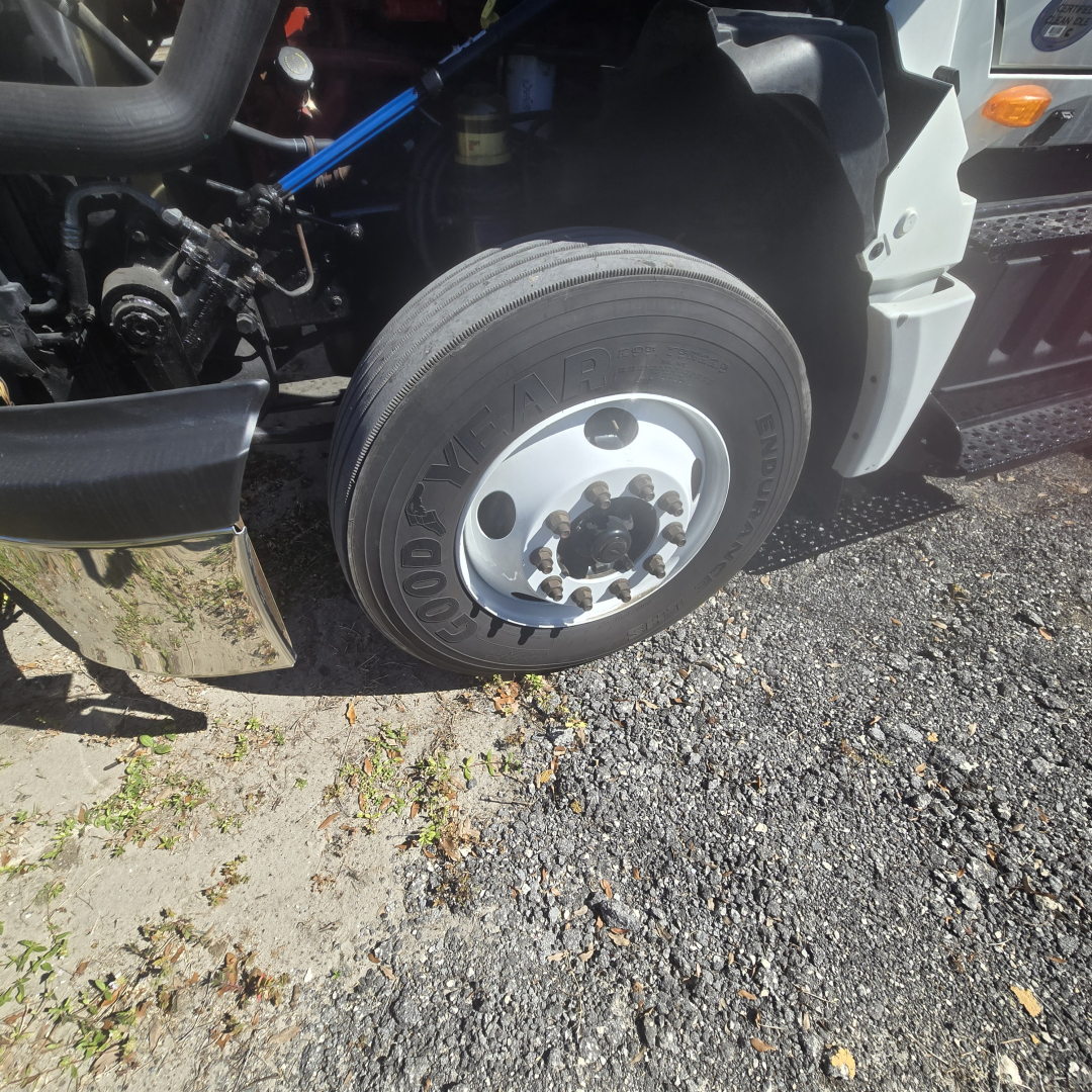 Truck front wheel and fender area showing Goodyear tire and hub, with part of the International LT625 conventional cab visible.