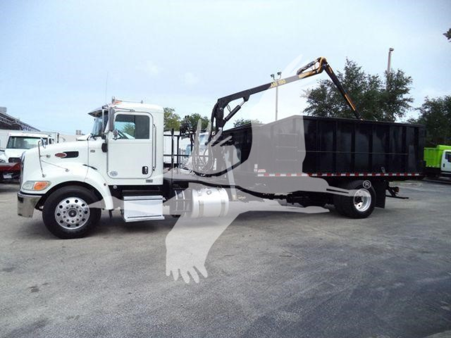 Truck with grapple loader on a white Peterbilt 337, side view showing a black dump bed and hydraulic arm, no visible text.