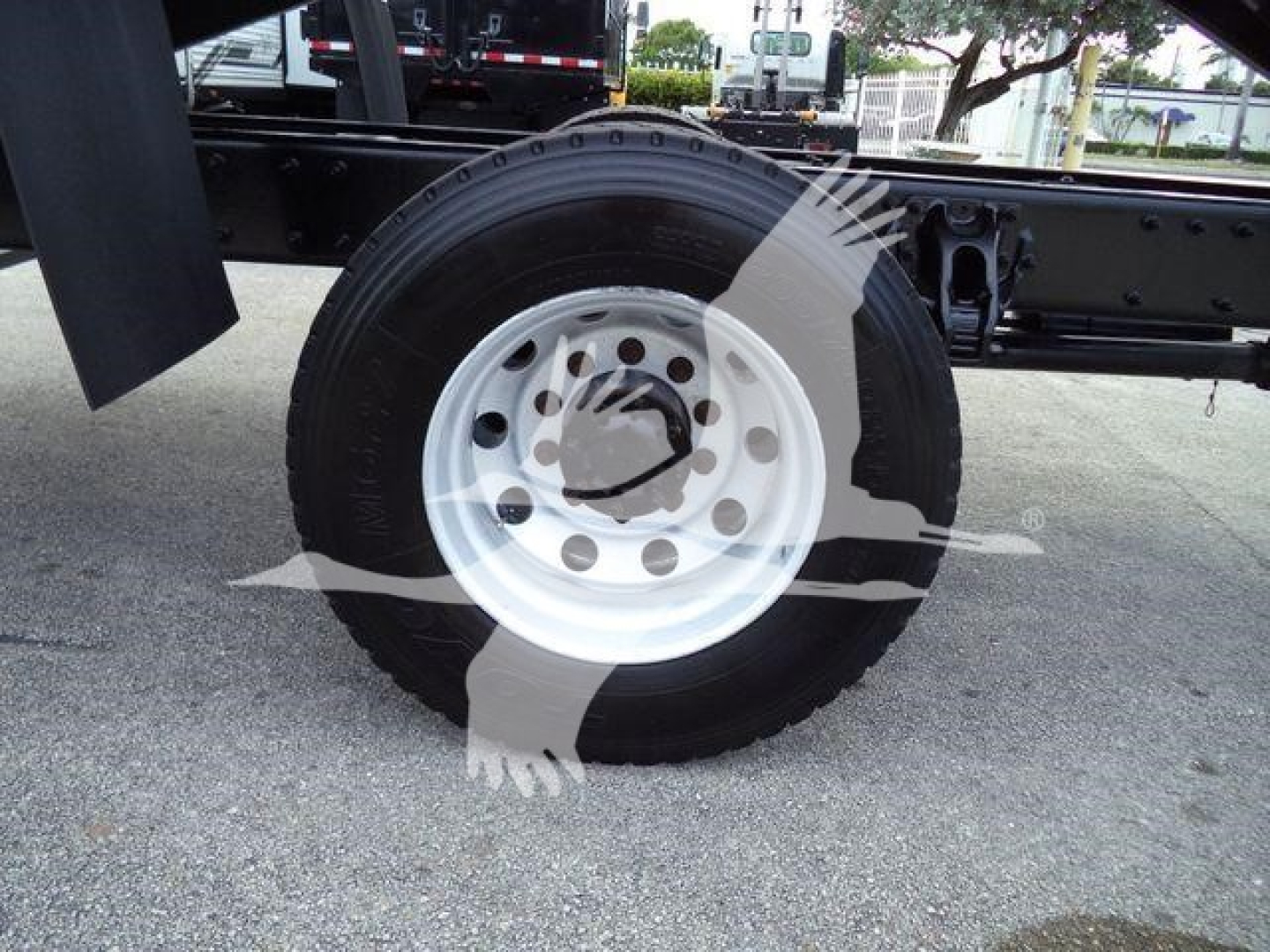 Truck wheel and frame showing white steel wheel with black tire, part of a Peterbilt 337 chassis, with stock number T18986 and grapple truck configuration visible.