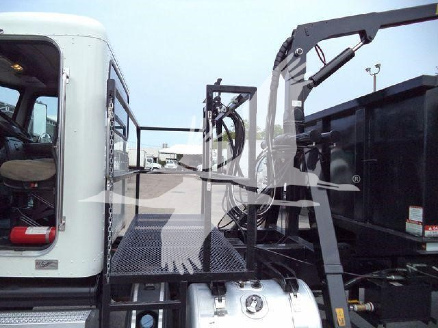 Peterbilt 337 truck with grapple loader visible on side, metal platform, hydraulics, cab window, and rear chassis components.