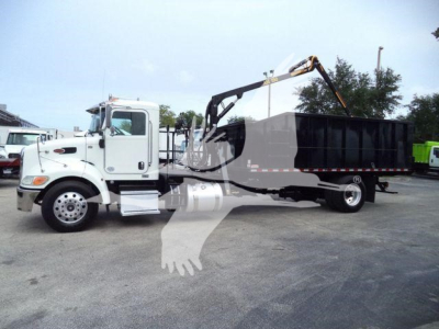 Truck with grapple loader on a white Peterbilt 337, side view showing a black dump bed and hydraulic arm, no visible text.