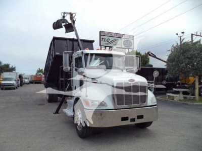 2020 Peterbilt 337 truck in a lot with grapple arm attached to rear, front grille, headlights visible.