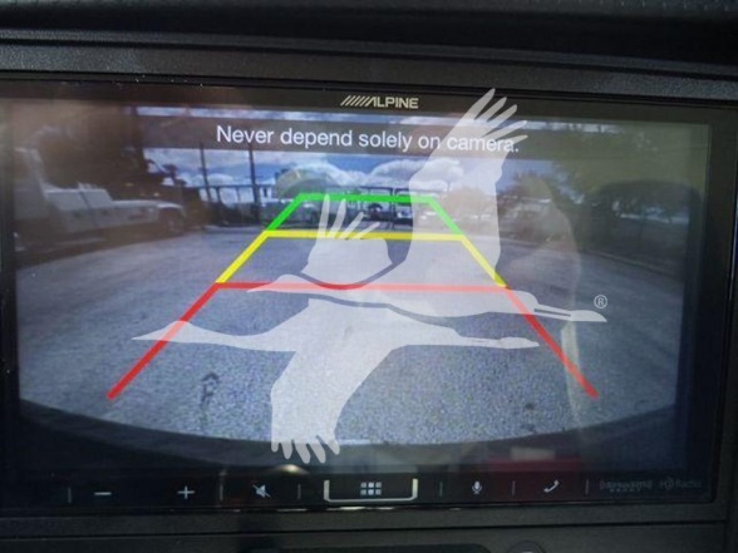 Backup camera display on Isuzu NPR HD showing guide lines (green, yellow, red) with 'Never depend solely on camera.' text overlaid.