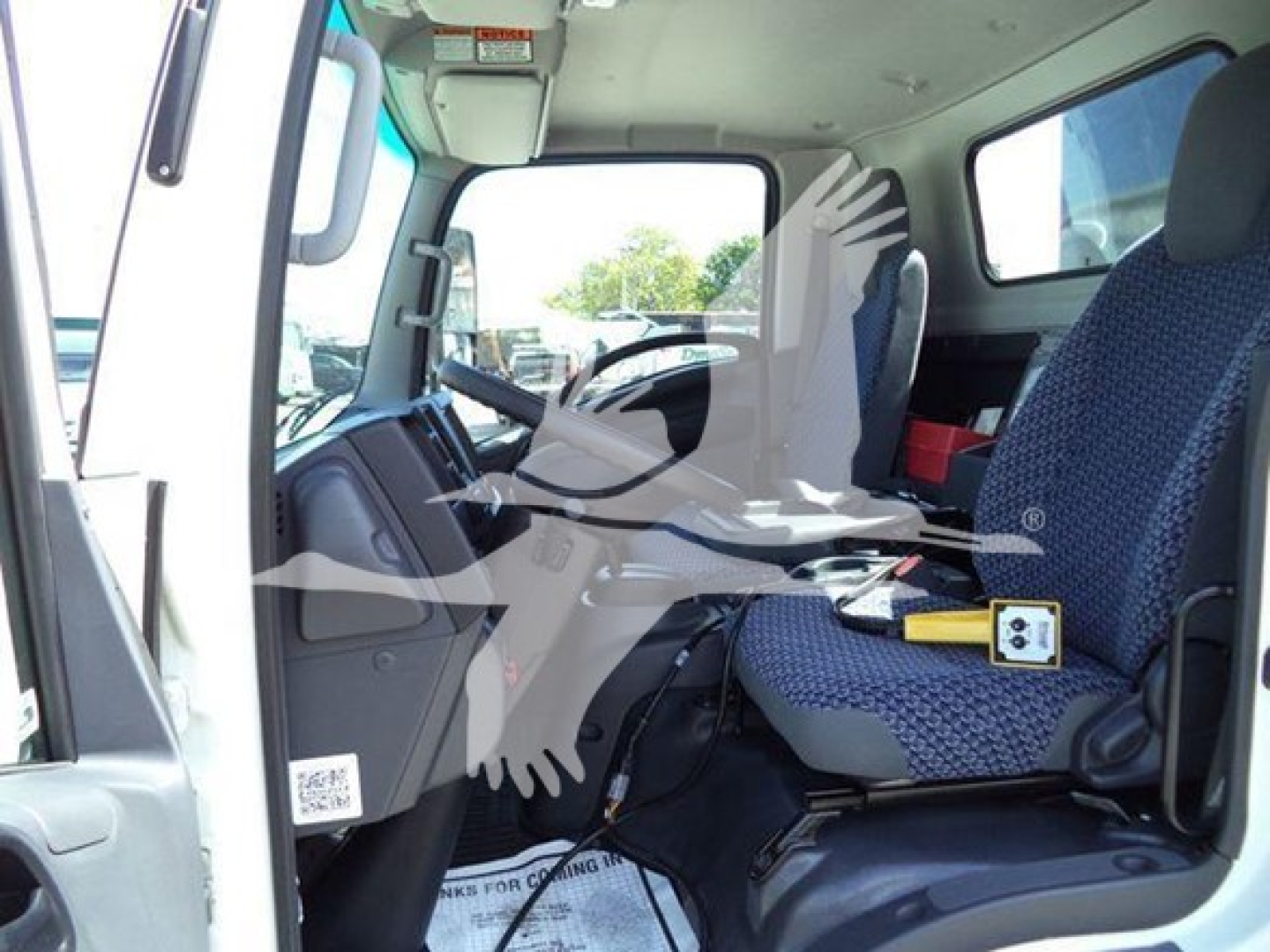 Isuzu NPR HD truck cab interior showing driver seat and passenger seat with steering wheel and dashboard in view.