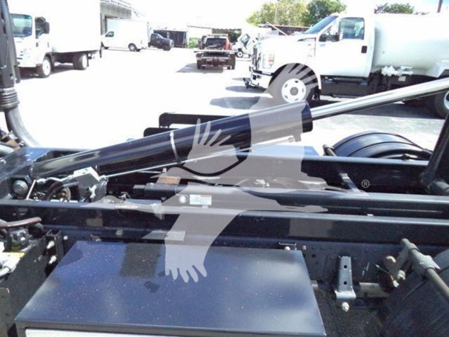 Isuzu NPR HD truck chassis showing hydraulic hooklift system with metal beams and tanks; no legible small text readable.